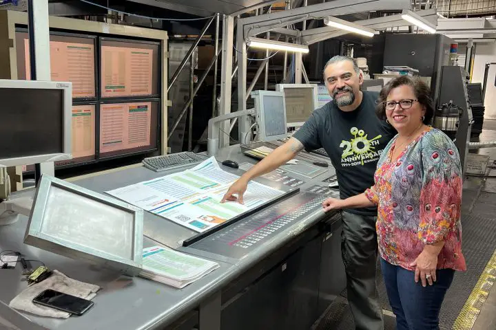 In a story about press check pressman and client standing next to a printing press